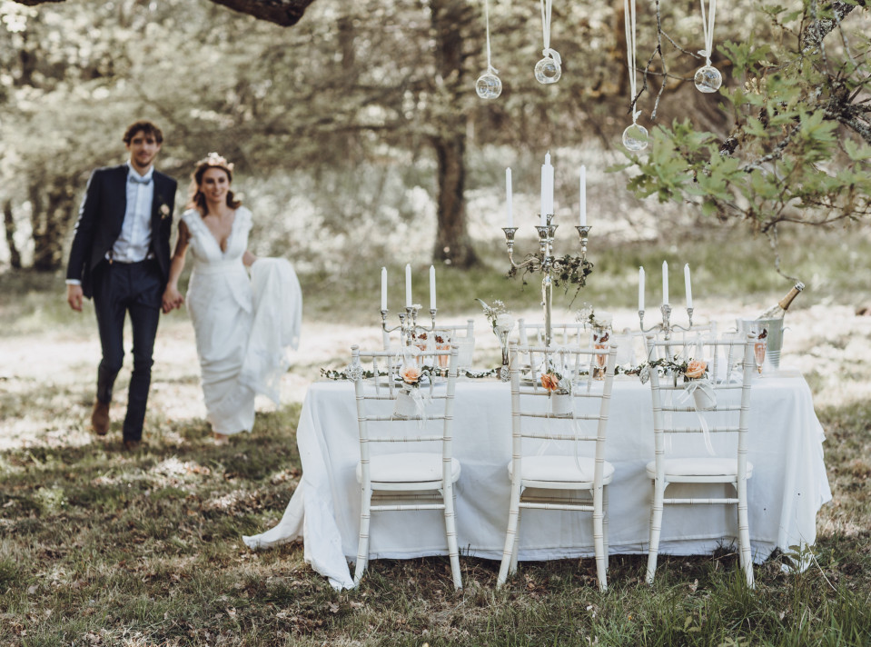 een bruid en bruidegom lopen door het bos met hun trouwtafel