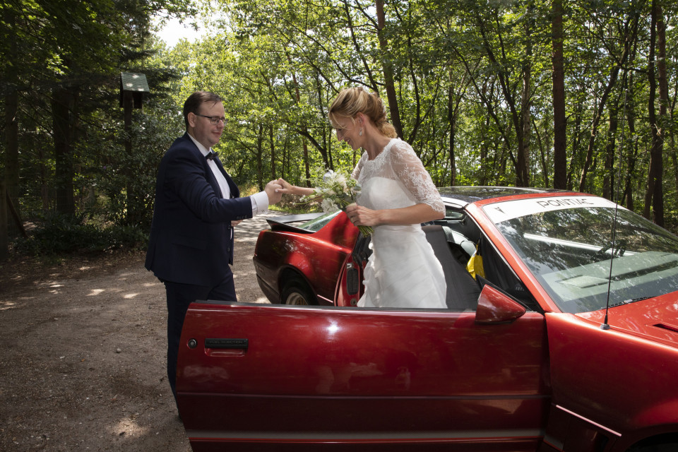 een man en een vrouw die naast een rode auto staan