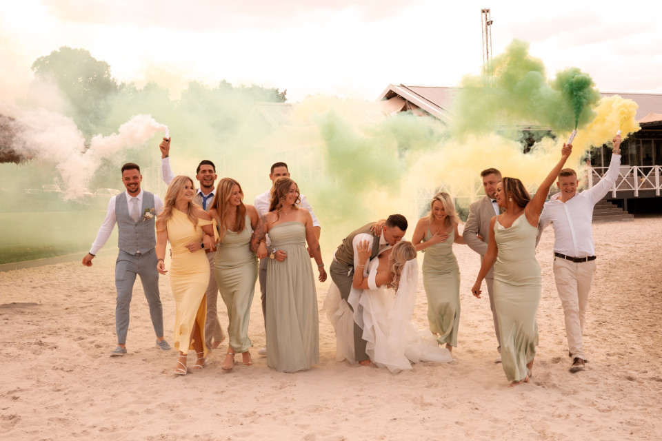 een grote groep mensen die poseert voor een foto op het strand