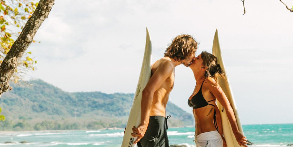 een man en vrouw kussen terwijl ze surfplanken vasthouden
