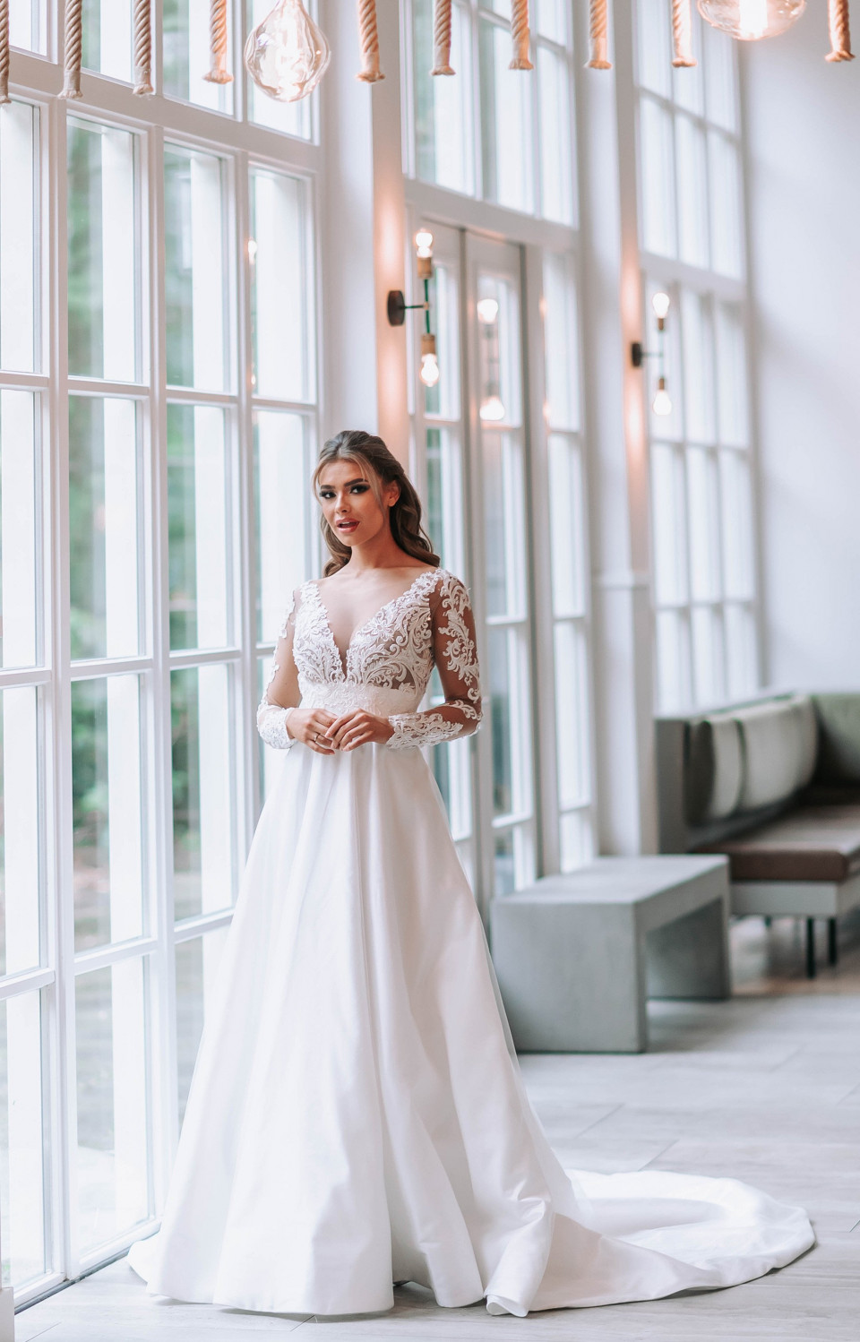 een bruid in een trouwjurk die poseert voor grote ramen