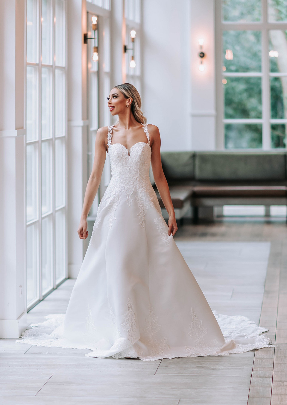 een bruid in een witte trouwjurk die staat in een grote kamer