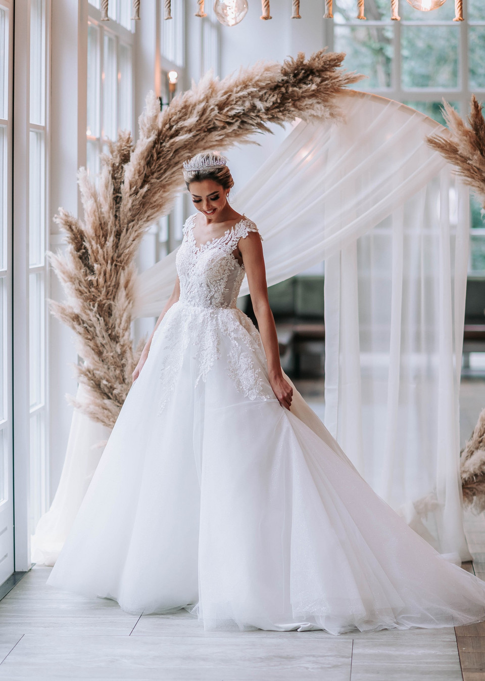 een bruid in een trouwjurk die poseert voor een grote krans