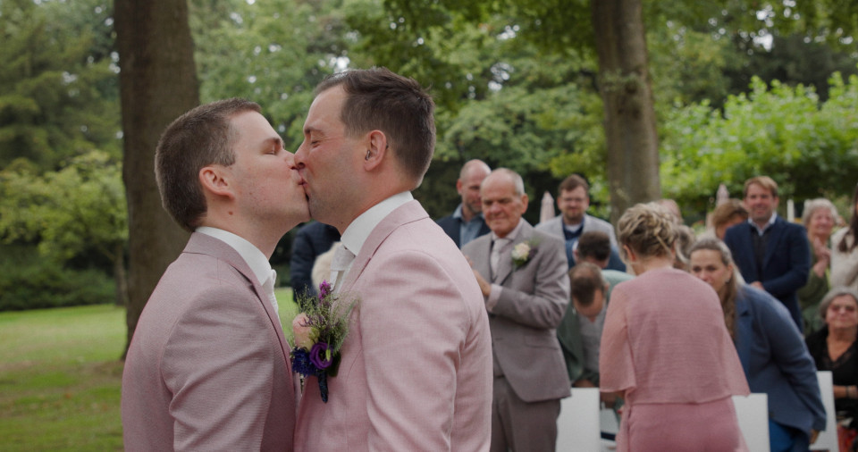twee mannen die elkaar kussen voor een menigte mensen