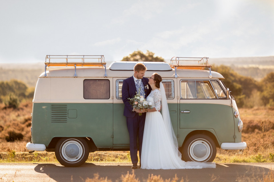 een bruid en bruidegom staan naast een camperbus