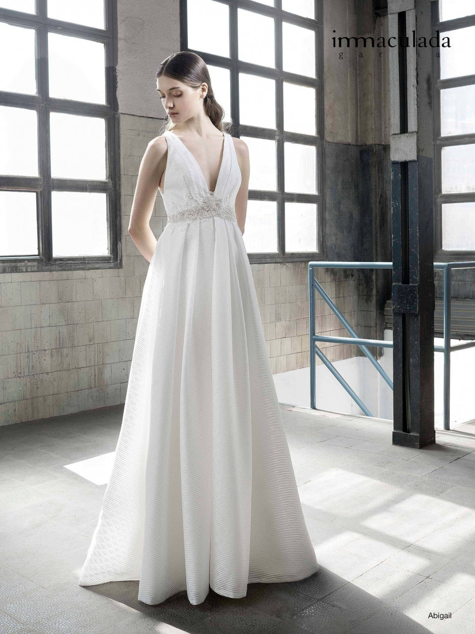 een vrouw in een witte trouwjurk die in een lege kamer staat