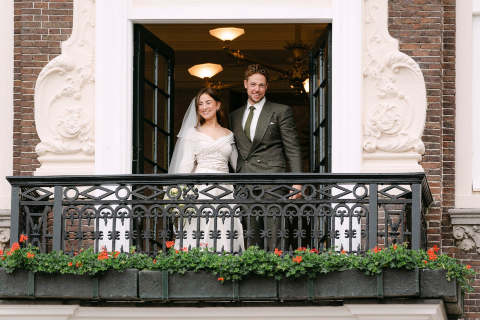 een bruid en bruidegom staan op het balkon van een gebouw