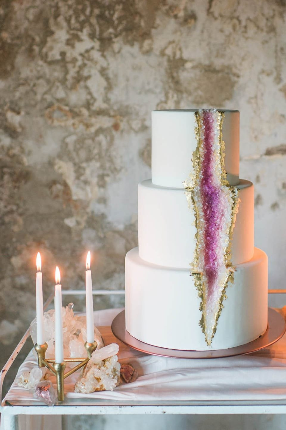 een bruiloftstaart met paarse en gouden kristallen