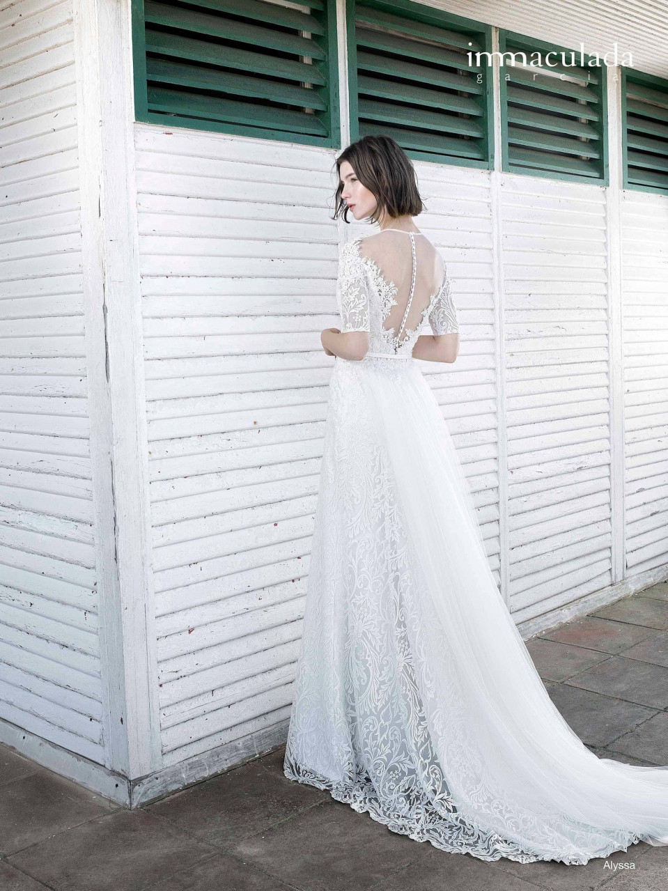 een vrouw in een trouwjurk die voor een wit gebouw staat