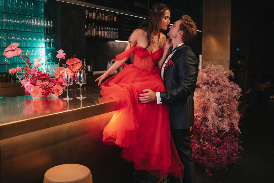 een man en vrouw in rode jurken zitten aan een bar