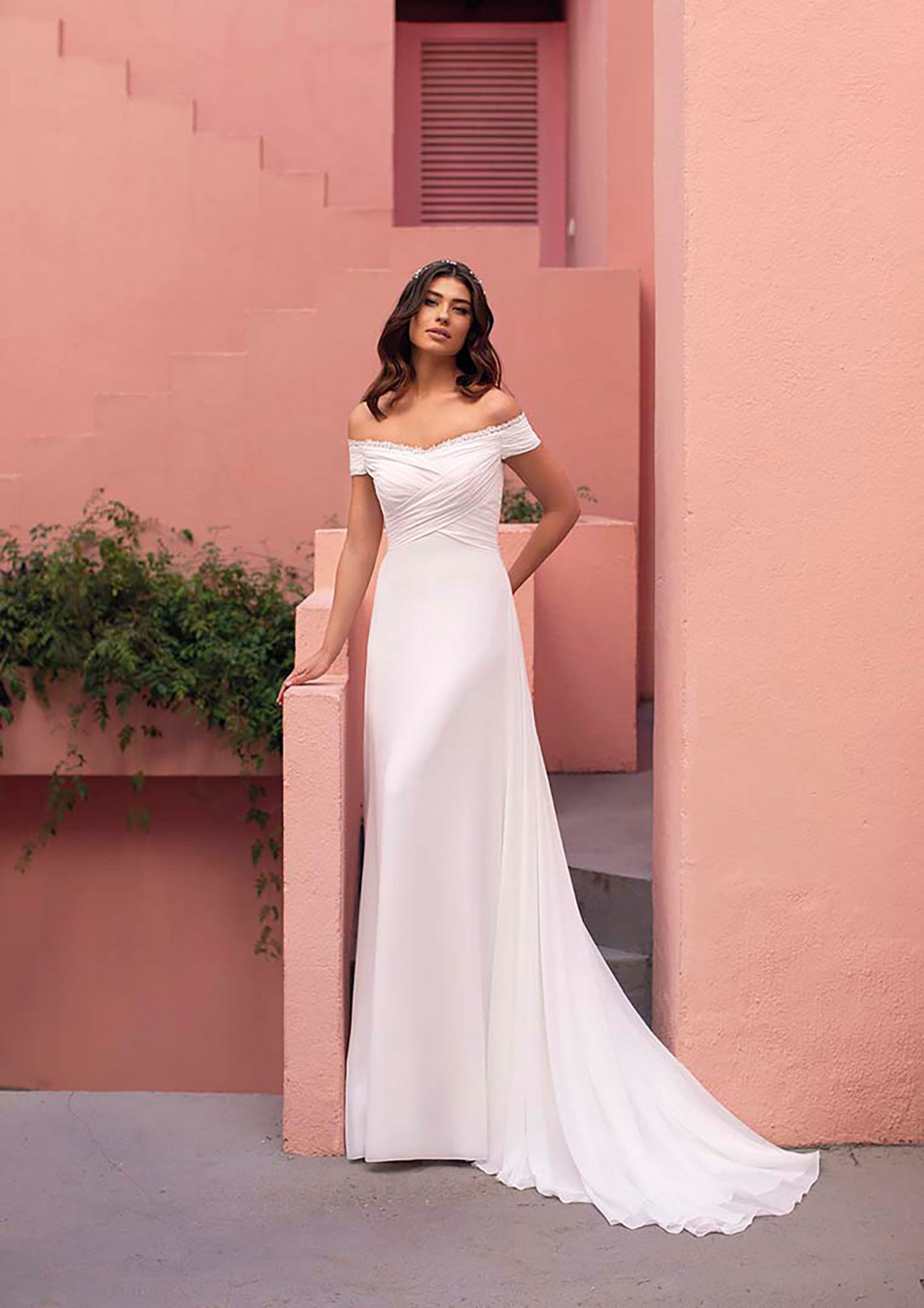 een vrouw in een witte trouwjurk staat voor roze muren