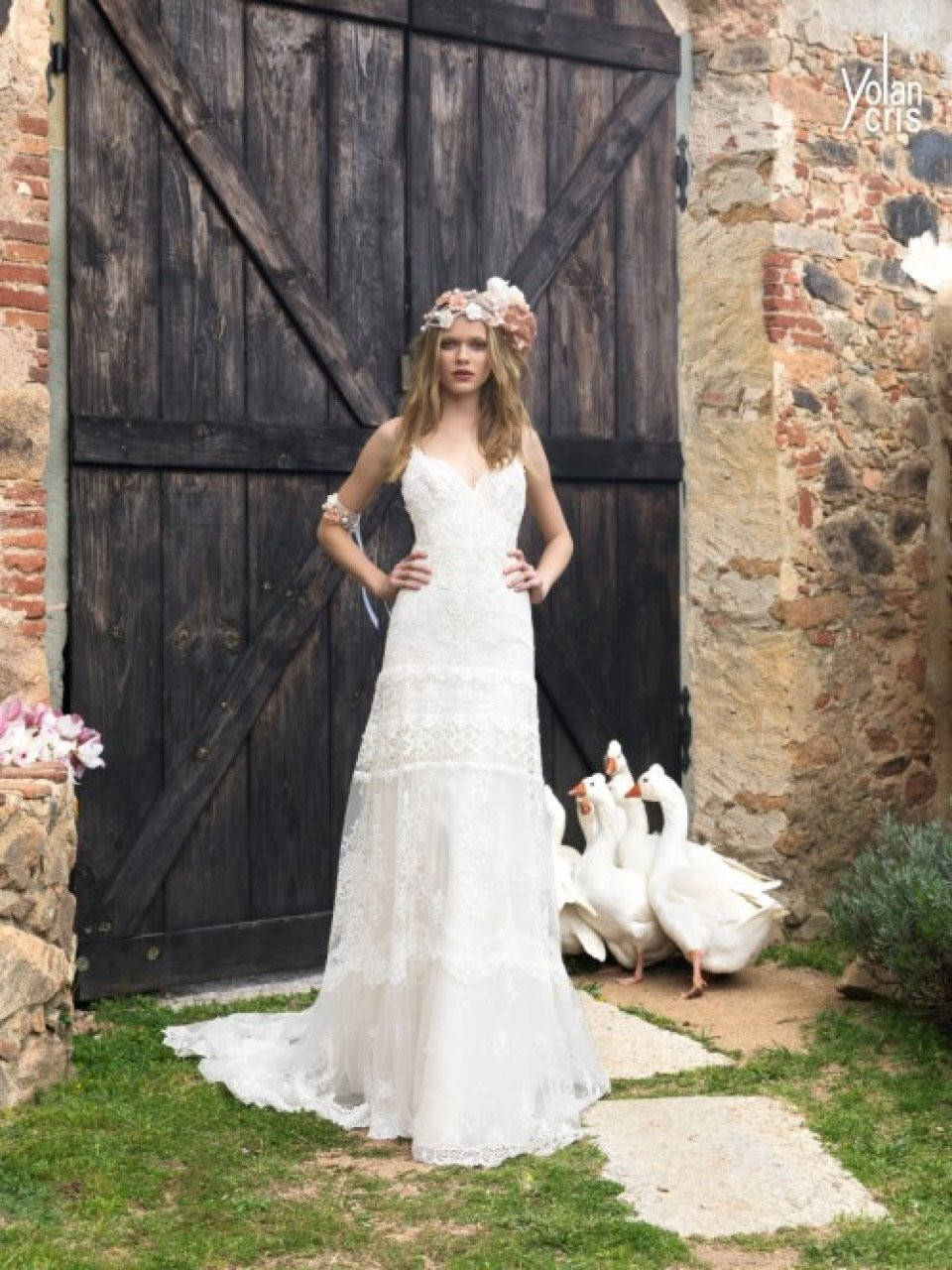 een bruid in een trouwjurk staat voor een schuurdeur