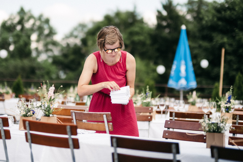een vrouw in een rode jurk staat aan een tafel met witte stoelen