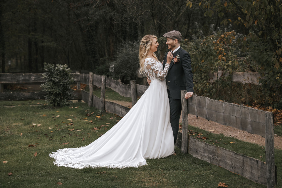 een bruid en bruidegom die naast een houten hek staan