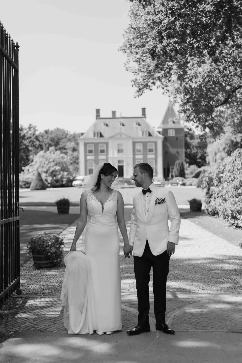 een zwart-wit foto van een bruid en bruidegom die hand in hand lopen