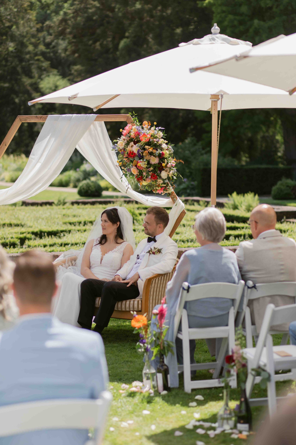 een paar mensen die onder parasols zitten op een bruiloft