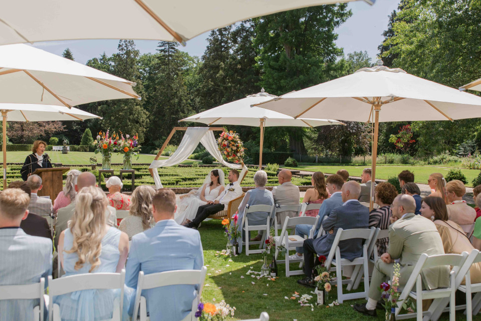 een grote groep mensen die onder parasols zitten