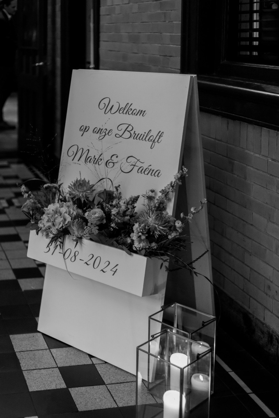 een zwart-wit foto van een bord met bloemen en kaarsen
