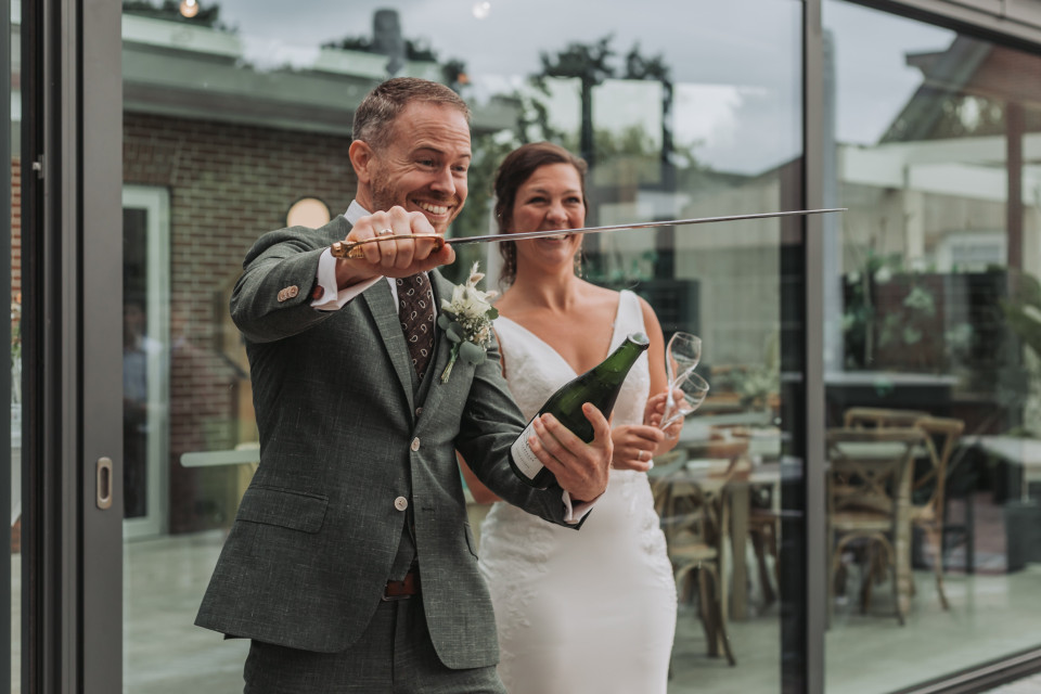 een bruid en bruidegom die een mes en champagne vasthouden