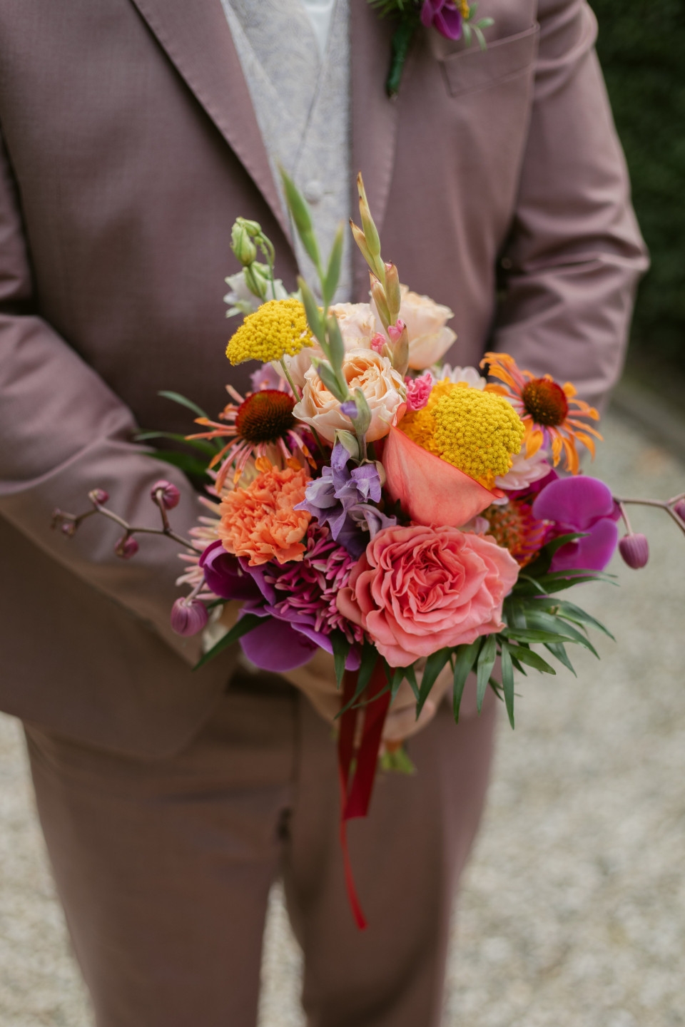een man in een pak die een boeket bloemen vasthoudt