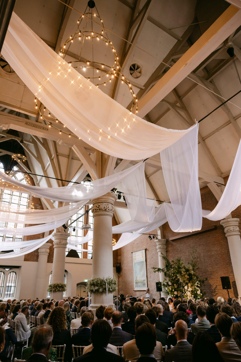een grote groep mensen die aan tafels zitten in een grote kamer