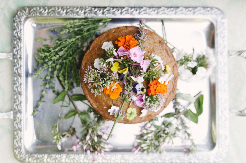 een bruidstaart met bloemen bovenop een zilveren dienblad