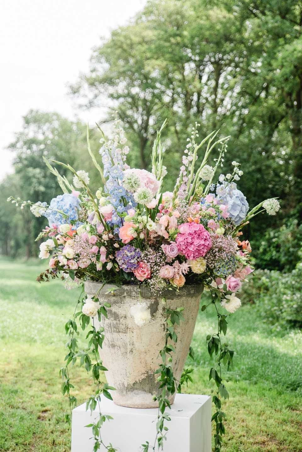 een grote bloemstuk in een vaas op een voetstuk