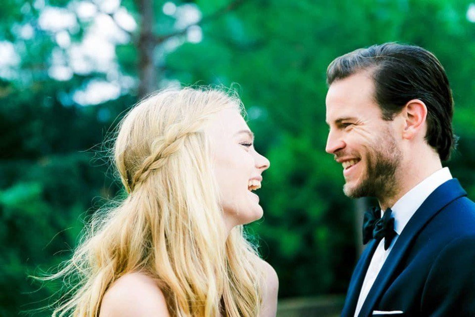 een man en vrouw lachen samen voor bomen