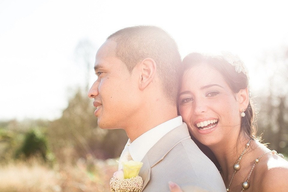 een bruid en bruidegom lachen naar elkaar in de zon