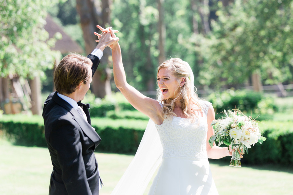 een bruid en bruidegom houden elkaars handen in de lucht