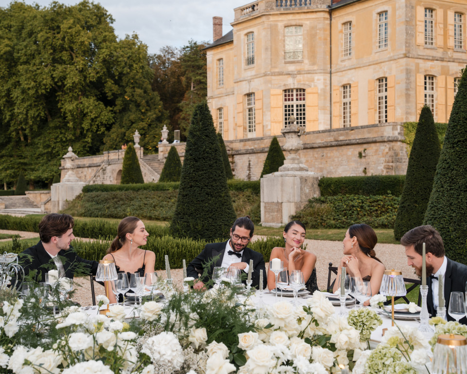 een grote groep mensen die aan een lange tafel zit