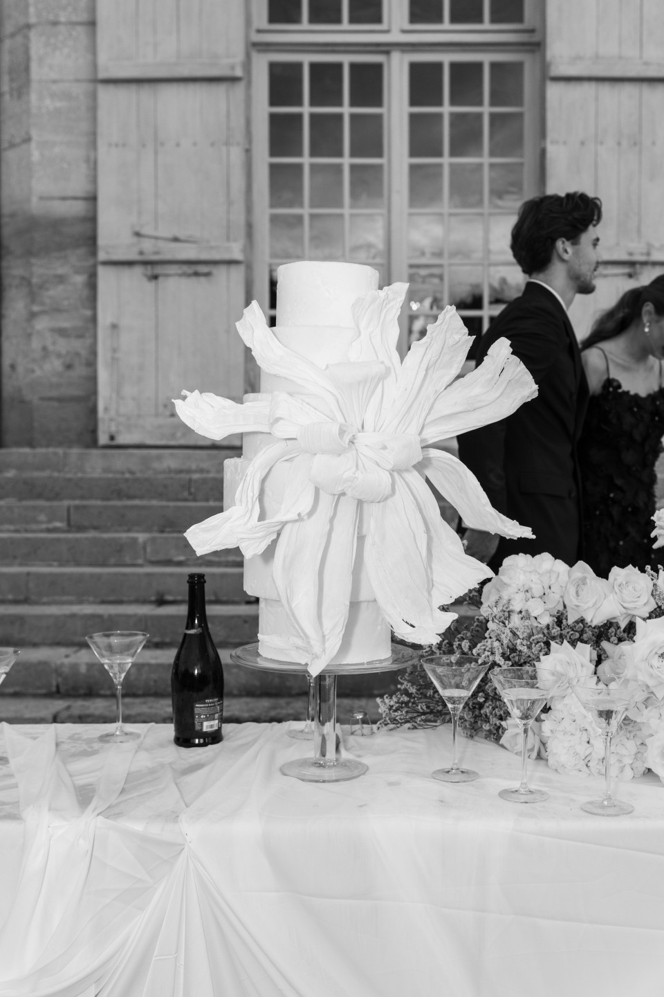 een zwart-wit foto van een bruid en bruidegom die kussen voor een bruidstaart