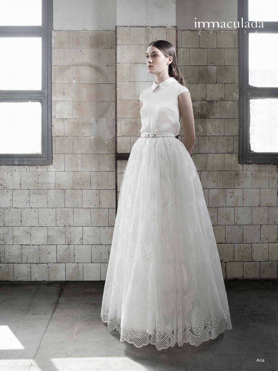 een vrouw in een witte trouwjurk die in een lege kamer staat