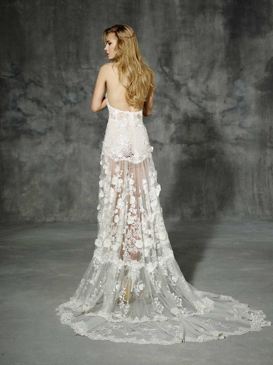 de achterkant van een vrouw die een trouwjurk draagt met een doorschijnende rok