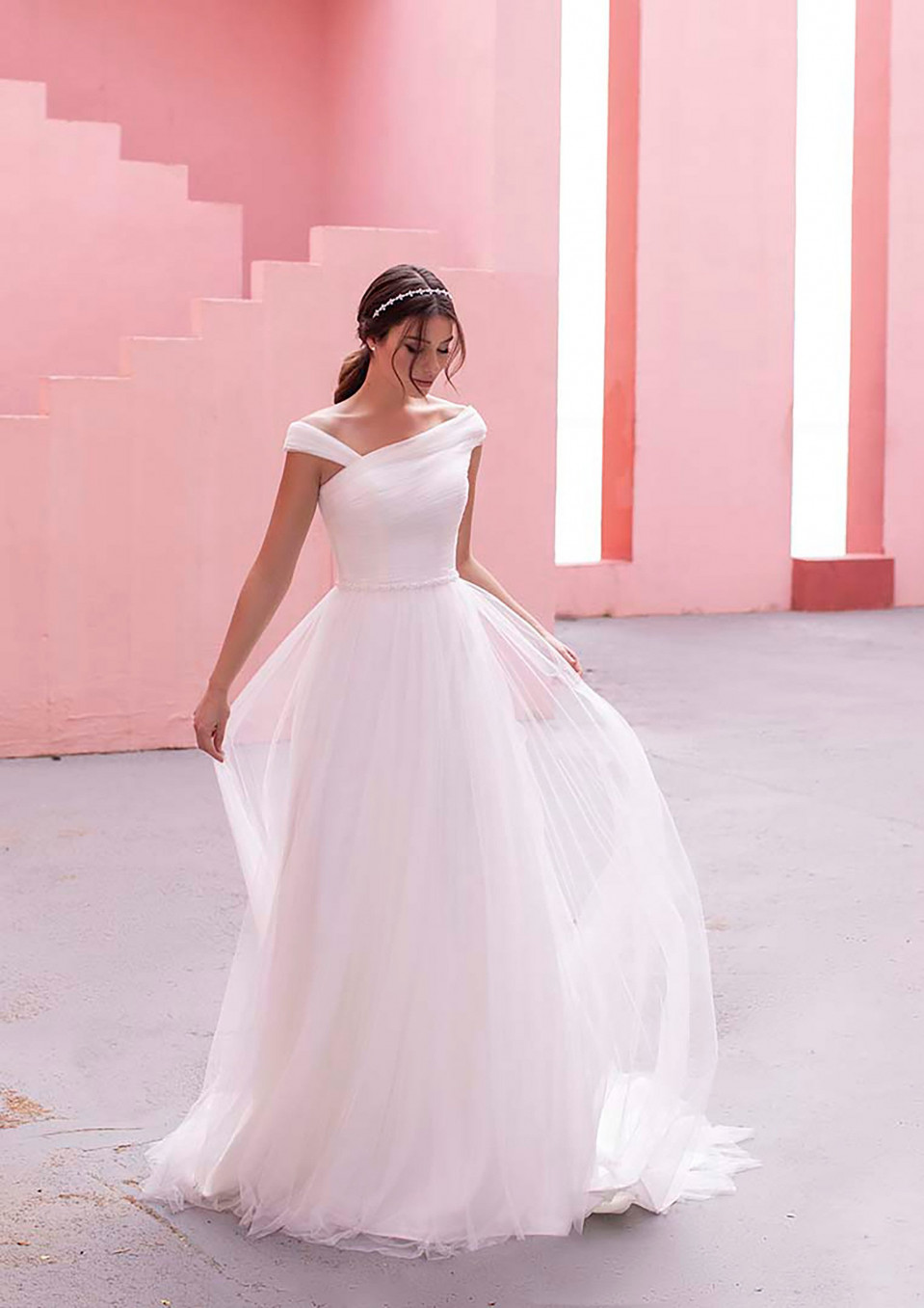 een vrouw in een trouwjurk staat voor roze muren