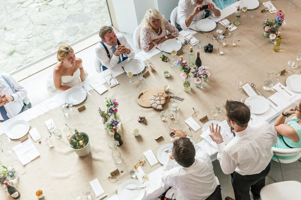 Tafel opgemaakt voor het bruiloftsdiner met bruidegom die speech geeft