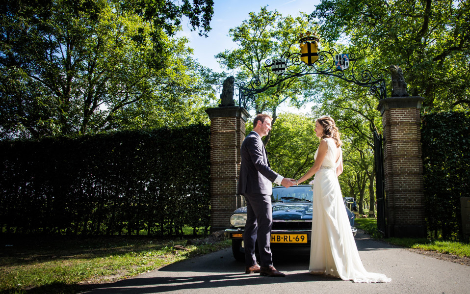 een bruidspaar dat voor een poort staat