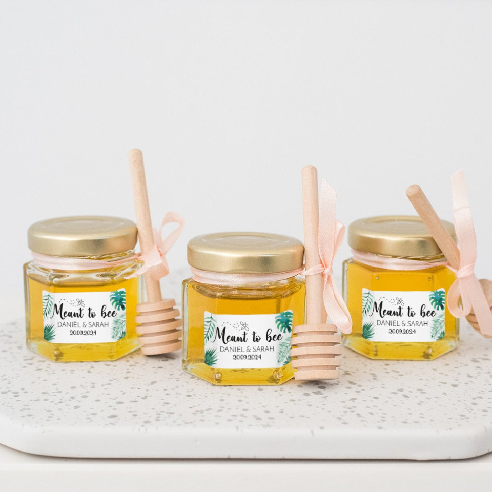 drie potten honing met houten stokjes