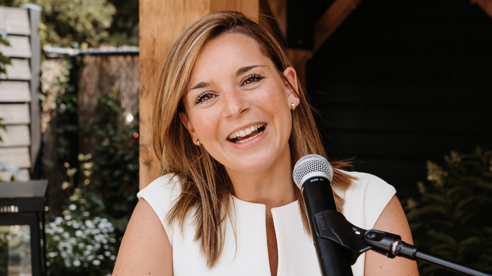 een vrouw glimlacht terwijl ze een microfoon vasthoudt