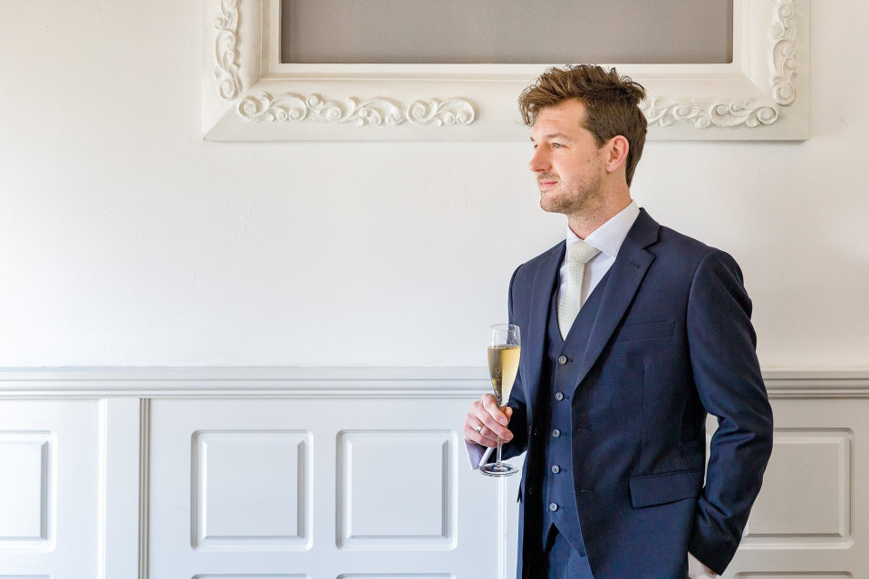 een man in een pak die een glas champagne vasthoudt