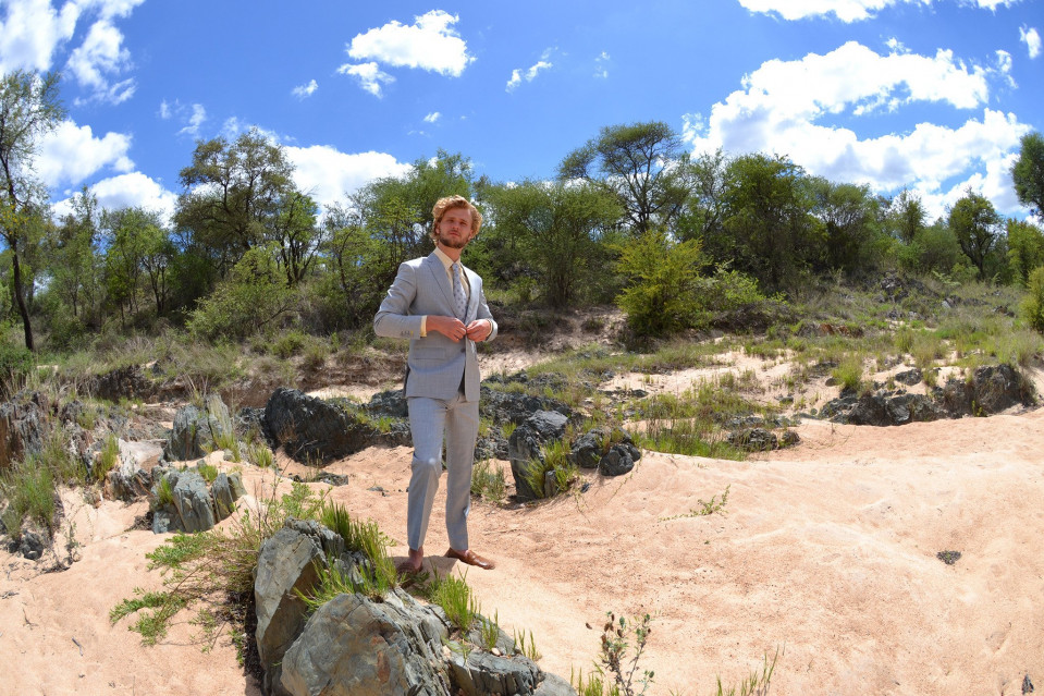 een man in een pak die op rotsen in de woestijn staat