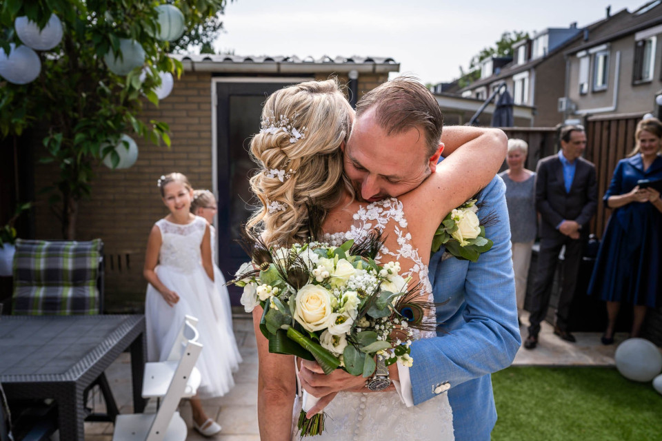 een bruid en bruidegom omarmen elkaar in de achtertuin van hun huwelijk