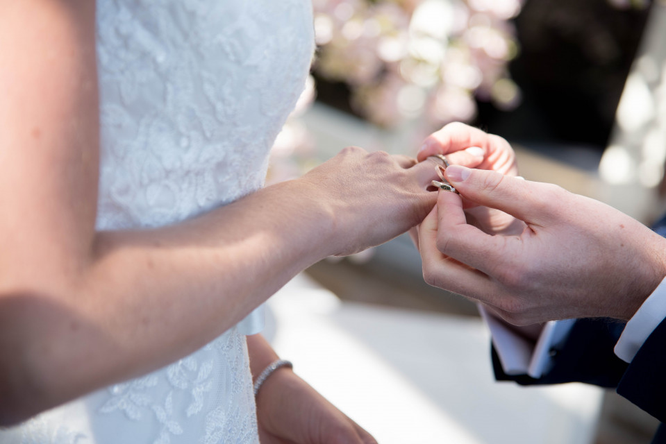 een man die een trouwring om de vinger van een vrouw doet