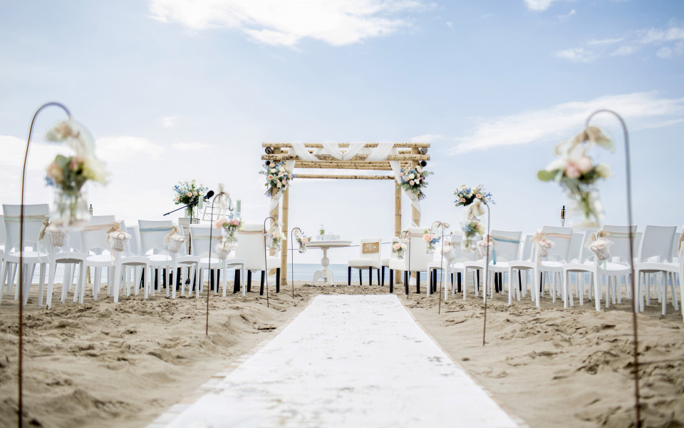 een huwelijksceremonie op het strand met stoelen en bloemen