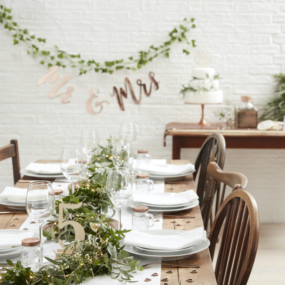 een tafel gedekt voor een bruiloftsreceptie met groen en bloemen