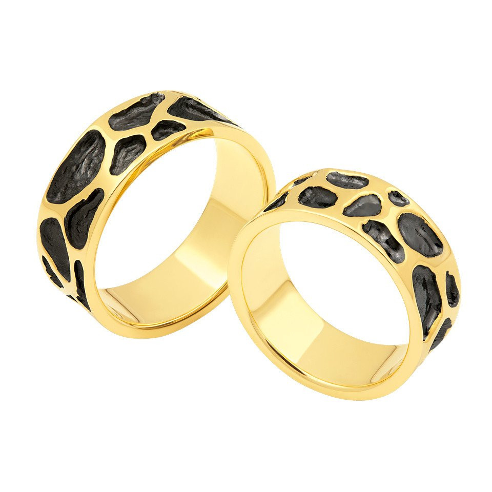 twee gouden en zwarte trouwringen met zwart en witte patronen