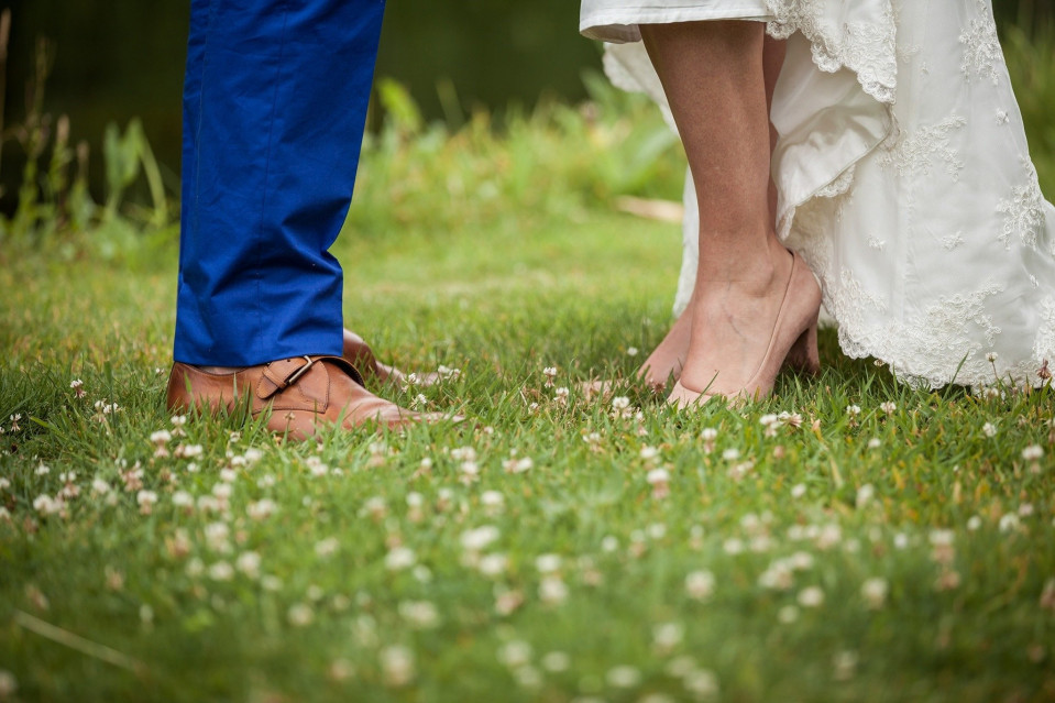 een bruid en bruidegom staan in het gras met hun voeten