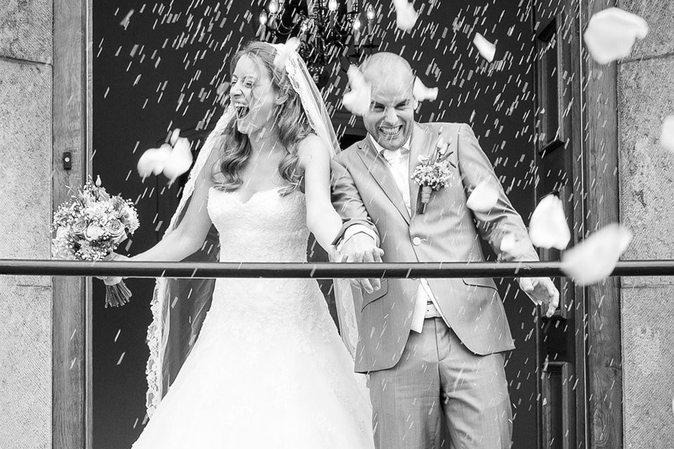een bruid en bruidegom staan voor een deur met confetti die valt