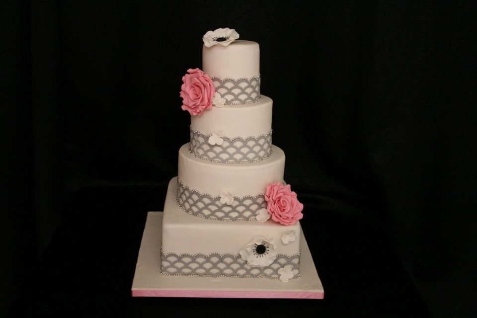 een drielaagse taart met roze bloemen bovenop