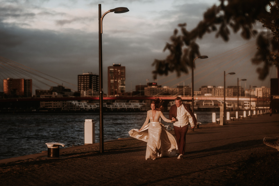 bruid en bruidegom die langs de waterkant lopen voor de stad
